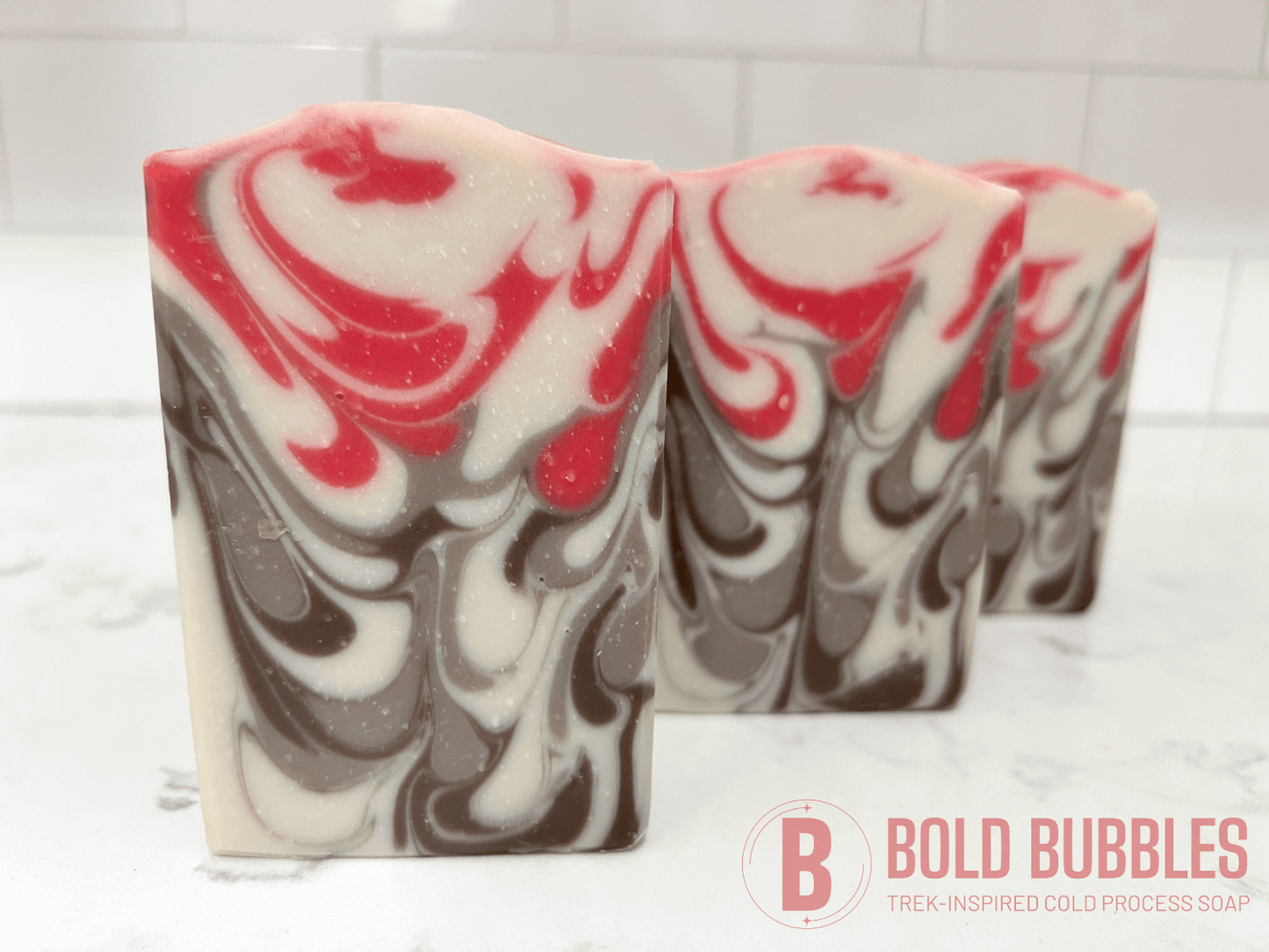 Bars of soap inspired by Jankom Pog from Star Trek: Prodigy. The hot pink, brown, and white bars were created with the drop swirl technique, and smell like rosemary mint.