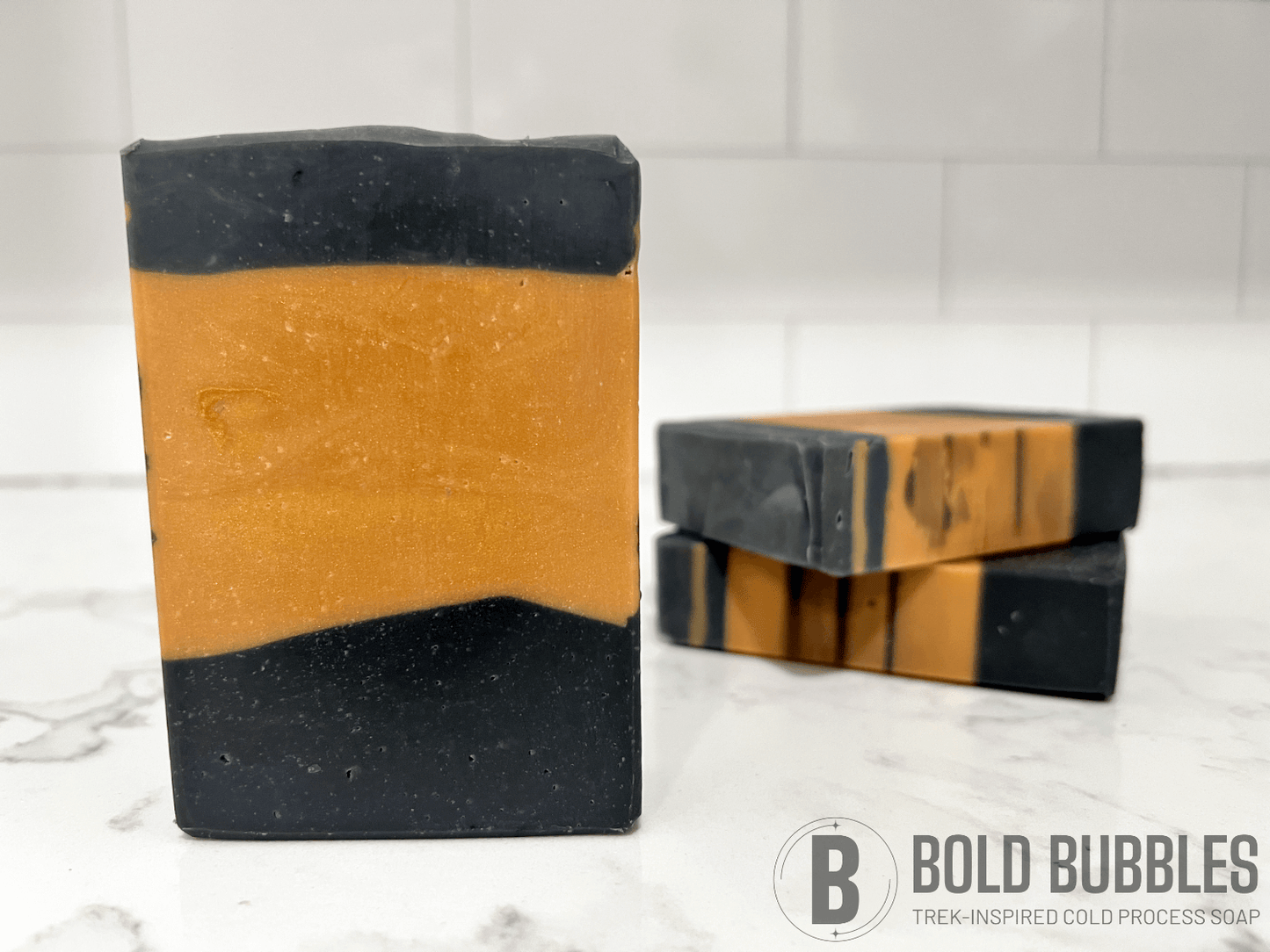 Gold and black bars of soap inspired by the design of the uniform Worf wore in Star Trek: The Next Generation. The bars are scented with lilac.