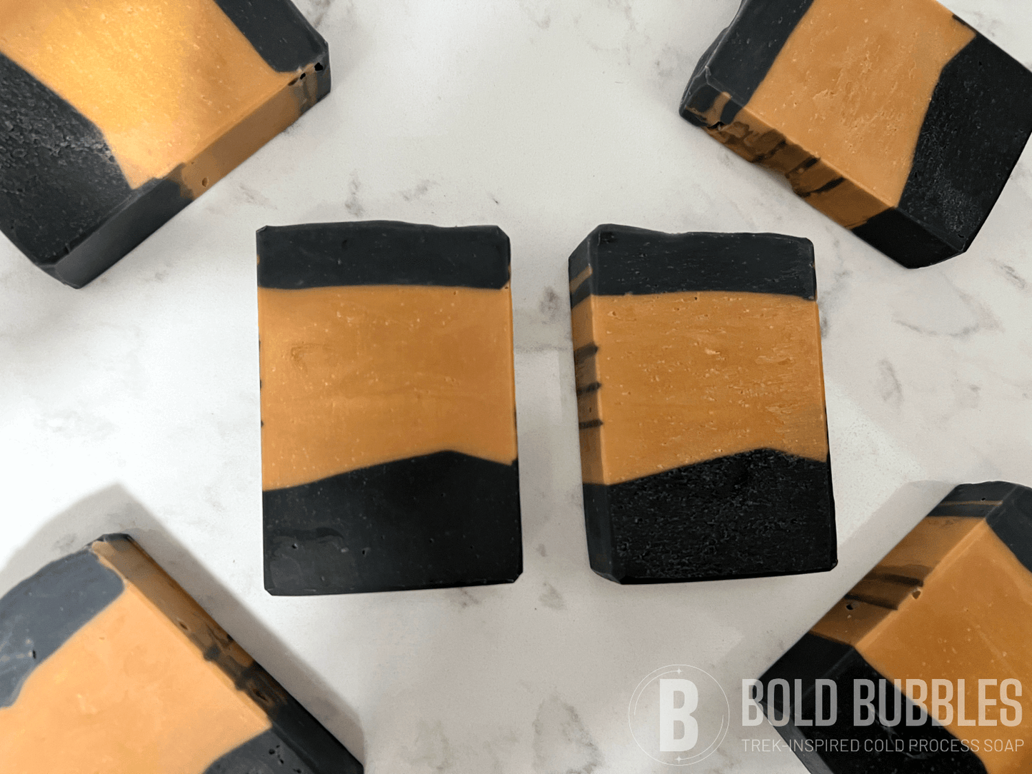 Gold and black bars of soap inspired by the design of the uniform Worf wore in Star Trek: The Next Generation. The bars are scented with lilac.