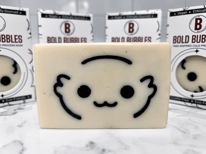 A white bar of soap with the outlines of a cute creature's face called a Moopsy in black. The design was inspired by the adorable but deadly creature from Star Trek: Lower Decks. This soap comes in a variety of scents.