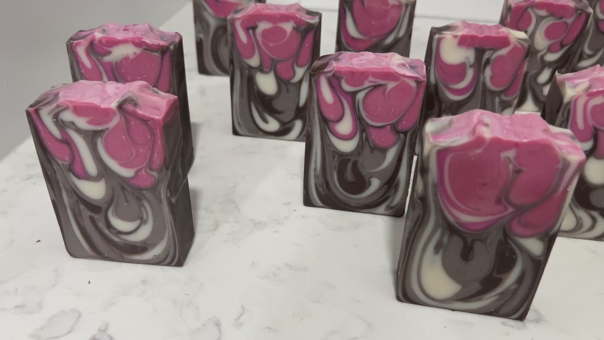 Bars of soap inspired by Jankom Pog from Star Trek: Prodigy. The hot pink, brown, and white bars were created with the drop swirl technique, and smell like rosemary mint.