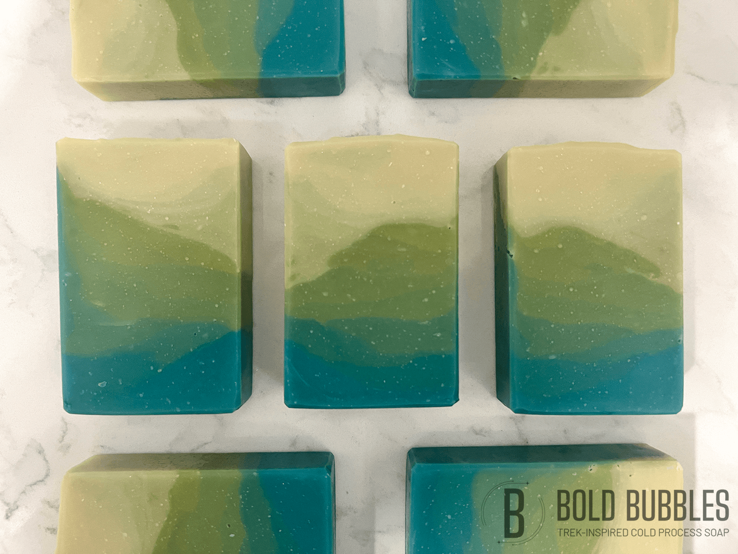 Bars of soap inspired by the relaxing beaches of Risa. The colors are a gradient of blue, to green, to sandy yellow. The scent is "sun and sand," a tropical breeze fragrance.